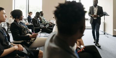 A speaker addressing a seated audience in a modern conference room.