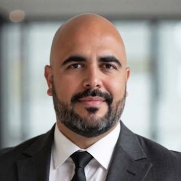 Professional man in suit and tie with a bald head and beard.