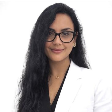 Professional woman with long black hair and glasses in a white blazer.