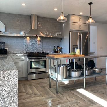 Modern kitchen with stainless steel appliances, granite countertops, herringbone floor