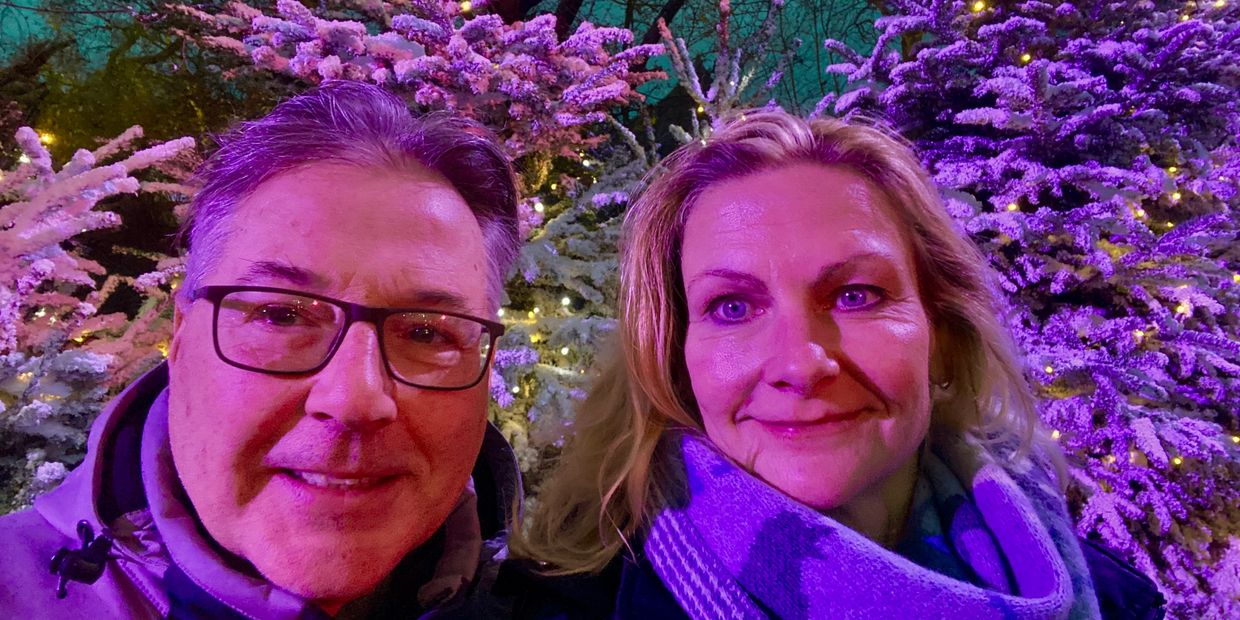 Ein lächelndes Paar vor Weihnachtsbäumen