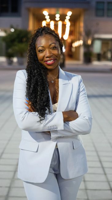 Confident woman in white suit smiling outdoors.