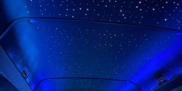 Car ceiling with blue lighting and star-like LED lights.