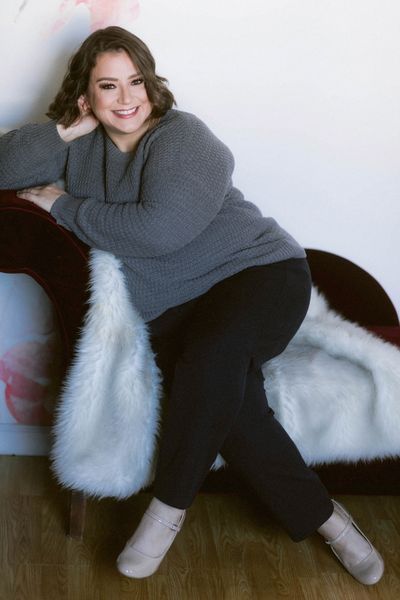 Image of Beth, a woman with brown hair and eyes wearing a grey sweater and navy pants.