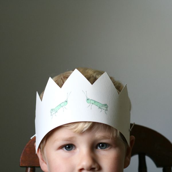 Handmade paper crown featuring grasshopper paintings, worn by a boy made by Renée Anne 