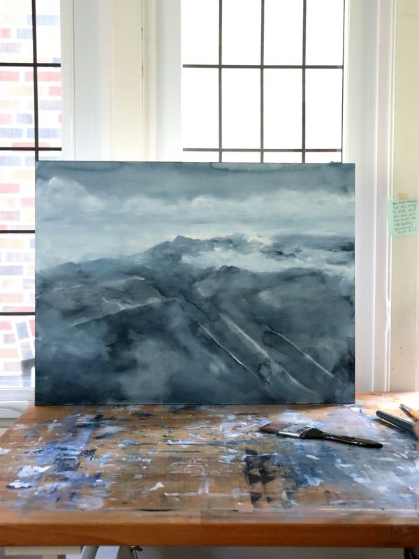Indigo blue watercolour painting of a rock landscape by the misty water in Renée Anne's studio.