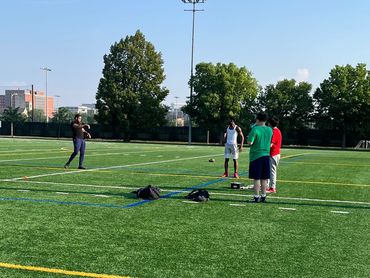 Group of people playing football on a sunny day on a green field.