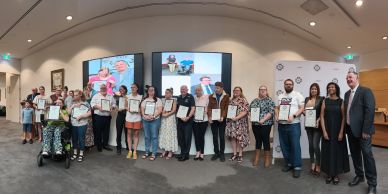 Group photo of award recipients holding certificates at a formal event.