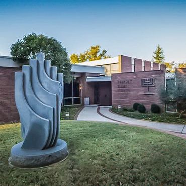 Modern synagogue building with a large menorah sculpture outside.