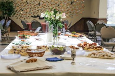 A table set with assorted snacks and flowers in a bright room.