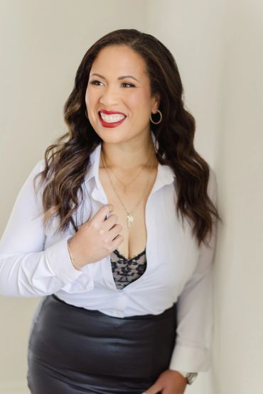 A smiling woman in a white blouse and black skirt.