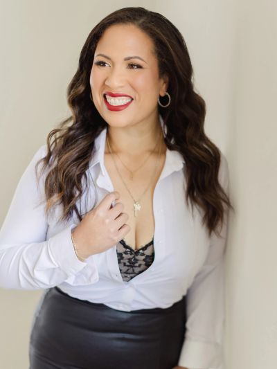 A smiling woman in a white blouse and black skirt.