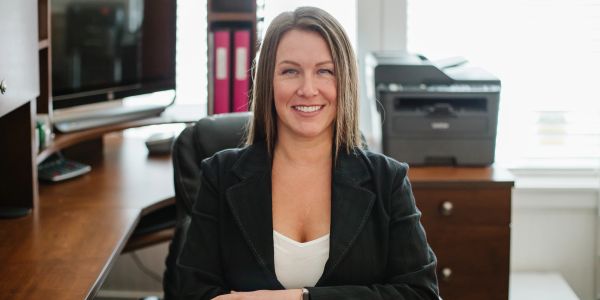 Smiling woman in business attire sitting at an office desk.