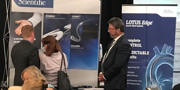 People discussing scientific and medical device posters at an event.