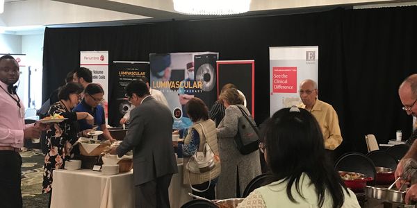 People serving and receiving food at a buffet during a conference event.