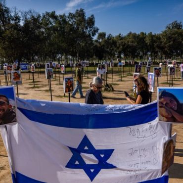 Memorial with photos and Israeli flag in outdoor setting.