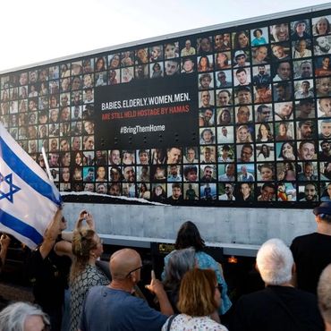 People observe a truck displaying photos of hostages taken by Hamas.