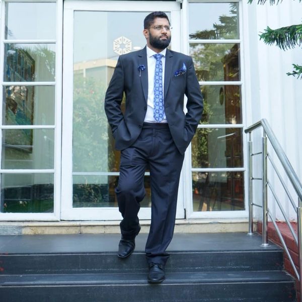 Man in black suit descending stairs outside a glass door.