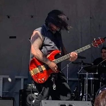 Musician passionately playing bass guitar on stage during a live performance.