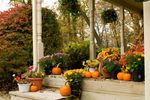 A cozy porch decorated with pumpkins and colorful autumn mums.