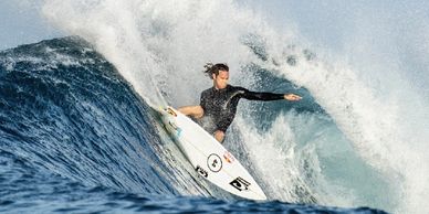 A surfer enjoys his repaired board by making a powerful turn on a wave.