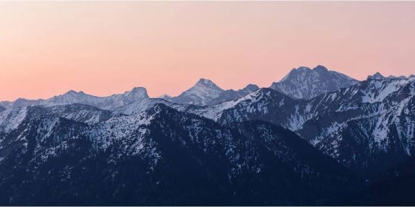 Mountain range during sunset with snow-covered peaks.