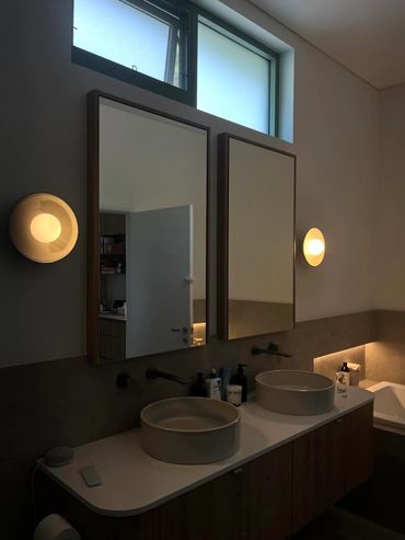 Modern bathroom with dual sinks, mirrors, and warm lighting.