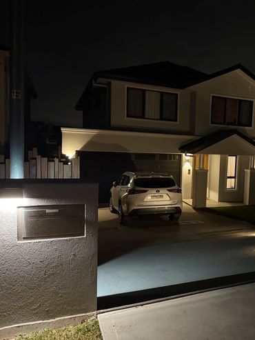 A modern two-story house illuminated at night with a car parked in the driveway.