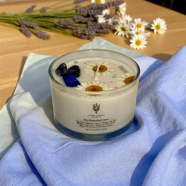 4 oz Sun-Drenched Linen candle adorned with dried daisies and blue lapis lazuli stones.