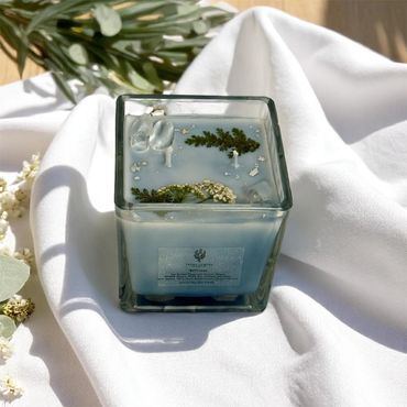 10 oz Stillness candle adorned with clear quartz crystals, fern leaves, and small white flowers.