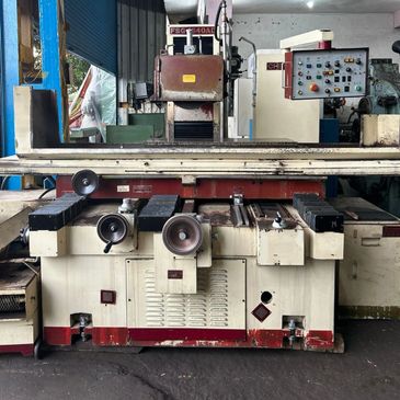 Industrial surface grinding machine in workshop setting.