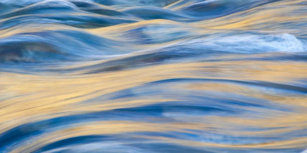 Flowing water reflecting golden sunlight in soft waves.