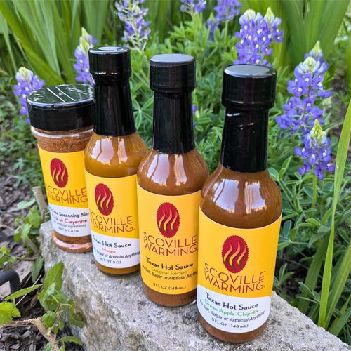 Scoville Warming hot sauces and seasoning with Texas bluebonnet flowers in the background.