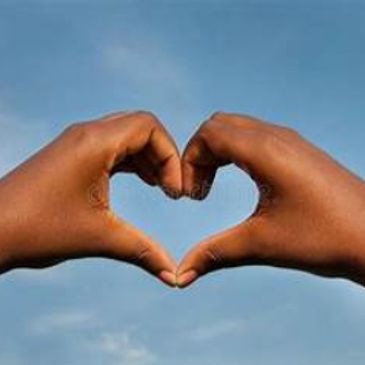 Hands forming a heart shape against the sky.