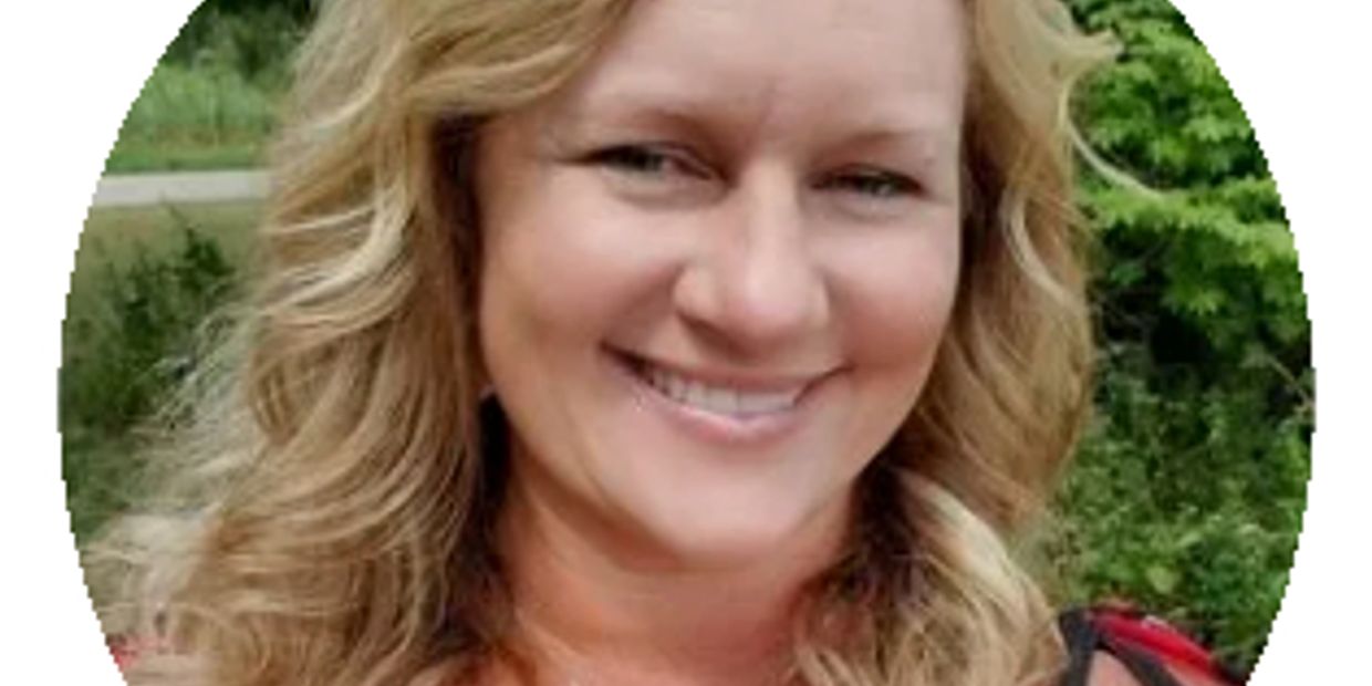 Smiling woman with wavy blonde hair outdoors.