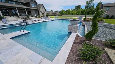 A modern backyard pool with clear water and surrounding greenery.