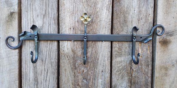Decorative metal wall hook with three hooks and floral detail.