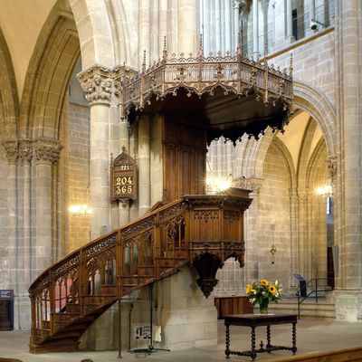Intricately carved wooden pulpit inside a stone church.