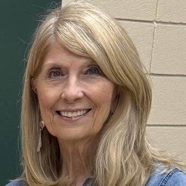Smiling middle-aged woman with blonde hair and a denim jacket.