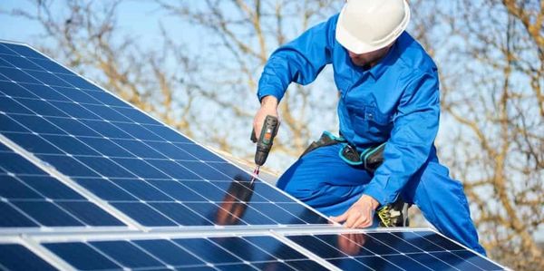 Professional roofer installing solar panels on a commercial property.