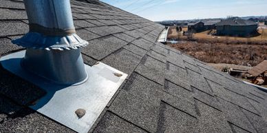 Detailed view of asphalt shingles and a metal chimney vent flashing on a residential roof.