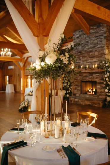 Elegant wedding table centerpiece with white flowers and candles in a rustic venue.