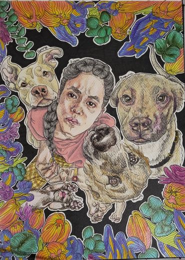 A person sitting cross-legged on the groud surrounded by 3 dog, 2 sleeping puppies and flowers