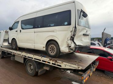 Damaged white van loaded on a flatbed truck.