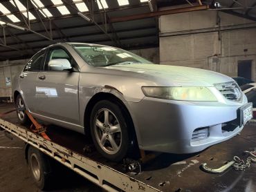 Silver Honda sedan with visible rust on the front fender on a tow truck.