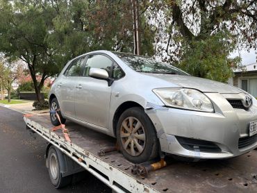 Silver car with front damage on a tow truck.