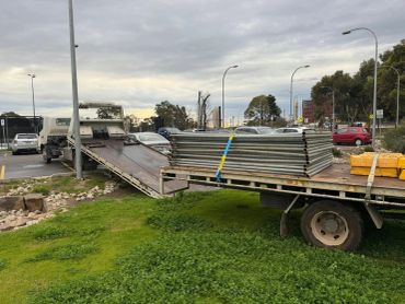 Flatbed trailer loaded with metal beams and pipes at construction site.