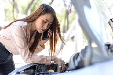 Woman calling for help by a broken car.