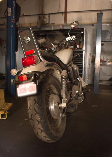 Suzuki motorcycle in a garage with worn tires.