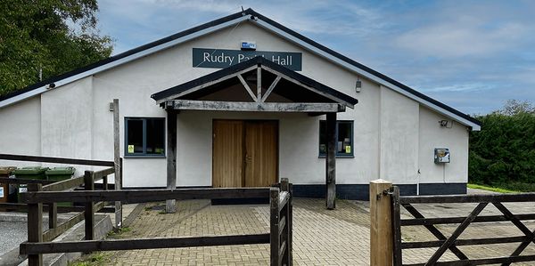 View of Rudry Parish Hall with wooden doors and fenced entrance.